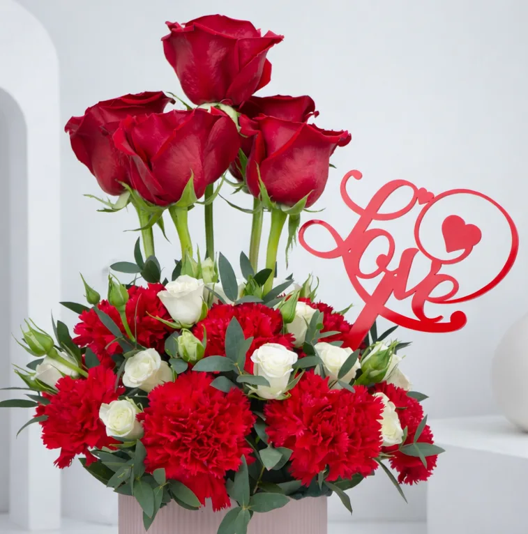 Valentine floral arrangement with red roses, carnations and love sign
