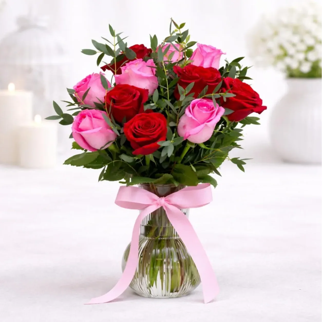 11 red and pink roses beautifully arranged in an elegant glass vase.
