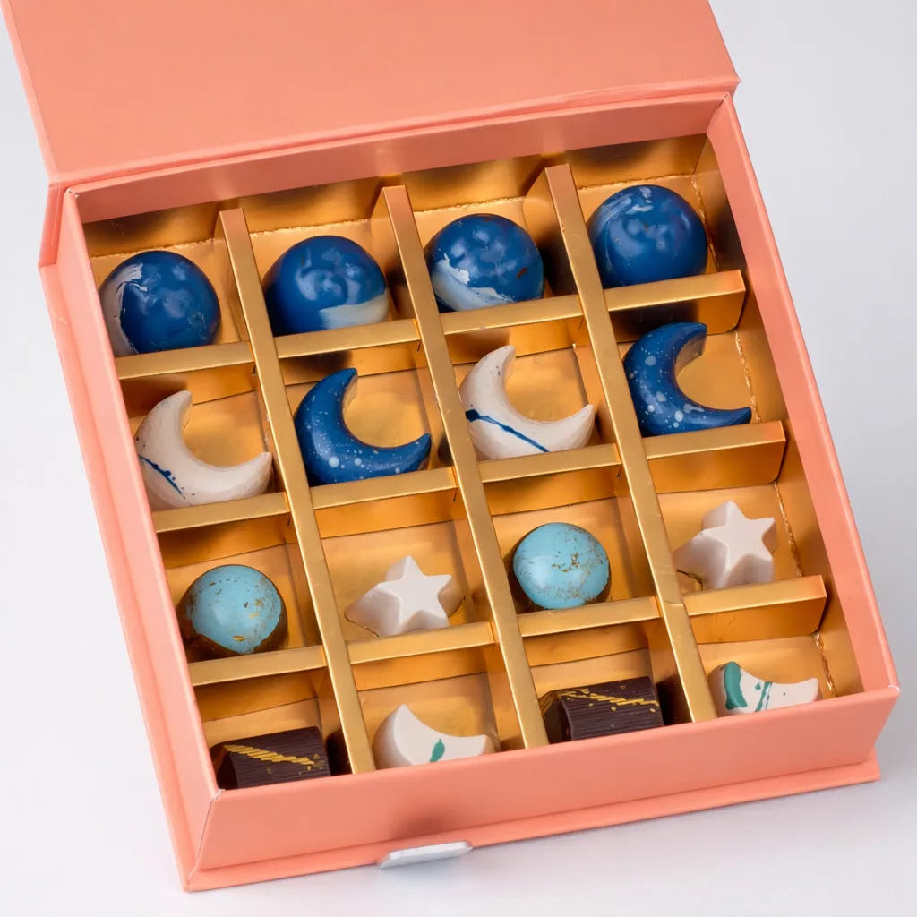 Luxury Thanksgiving chocolate gift box featuring artisanal celestial-shaped pralines in blue, white, and gold star and moon designs.
