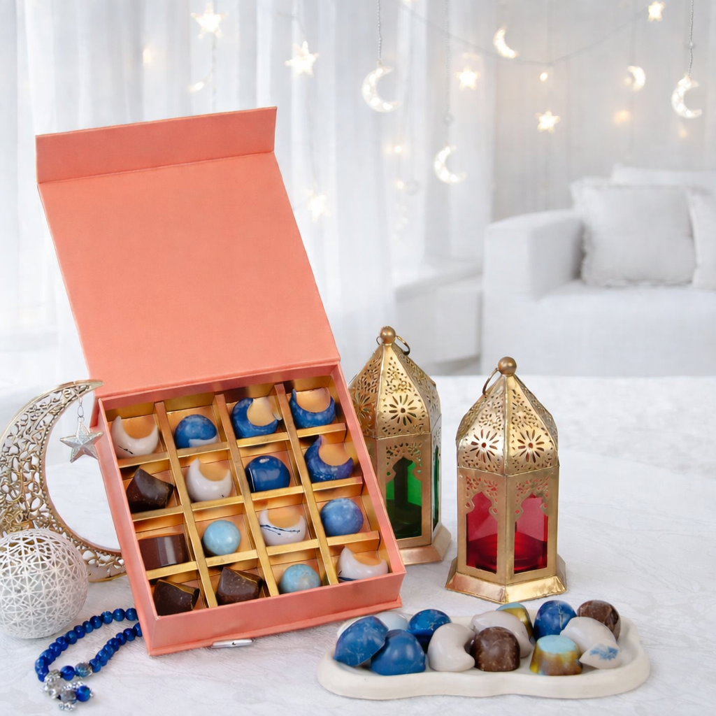 Pink gift box of assorted hand-painted chocolates styled with gold Ramadan lanterns and moon-and-star fairy lights.