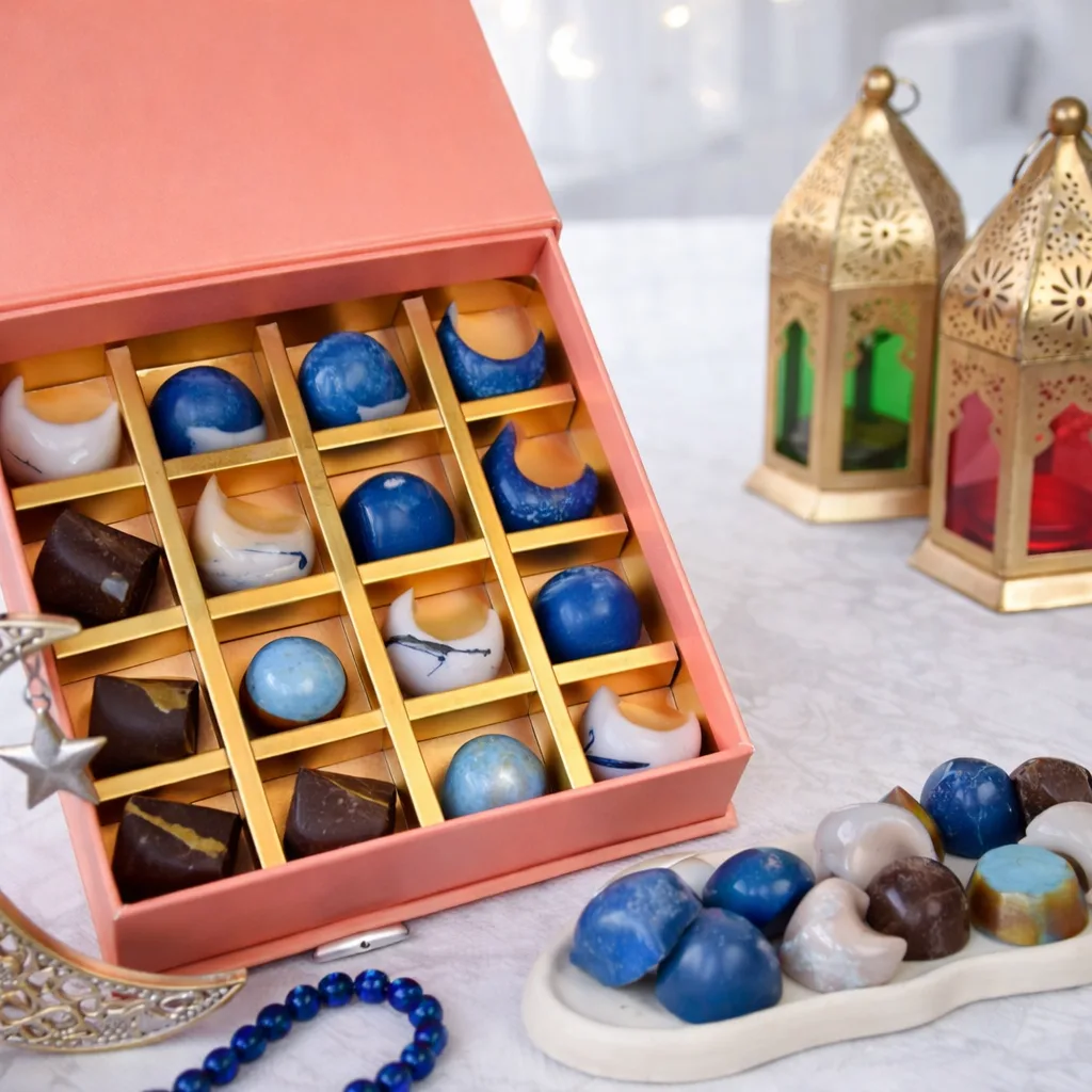 Close-up of blue and white marble-effect artisan chocolates in a pink gift box with gold lanterns.