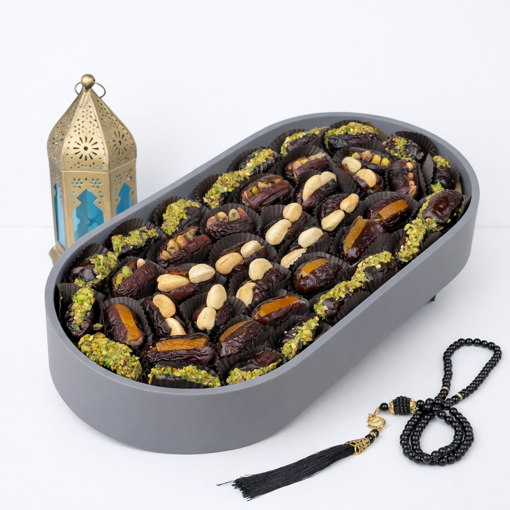 Tray of stuffed dates with pistachios, cashews, and dried apricots alongside black prayer beads and a gold Moroccan lantern.