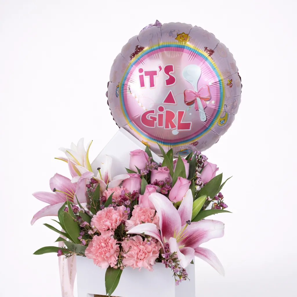 Close-up of pink lilies, roses, and carnations in a white flower box with an 'It's a Girl' balloon.