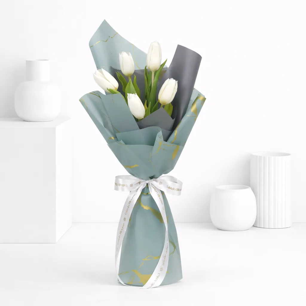White tulip bouquet wrapped in blue-grey and gold-print paper tied with a white Favish Blooms ribbon.
