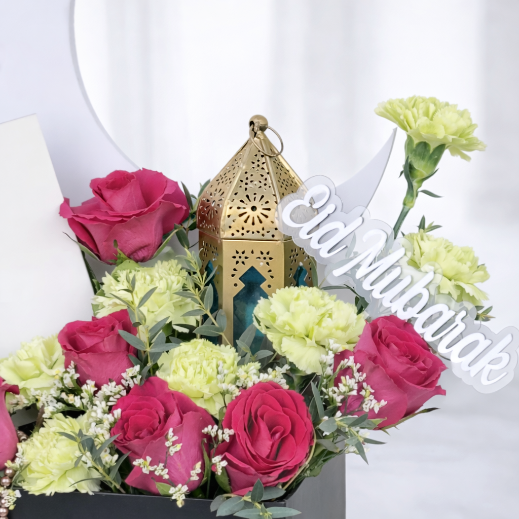 Close-up of Eid Mubarak flower box with pink roses, green carnations, and gold Moroccan lantern.