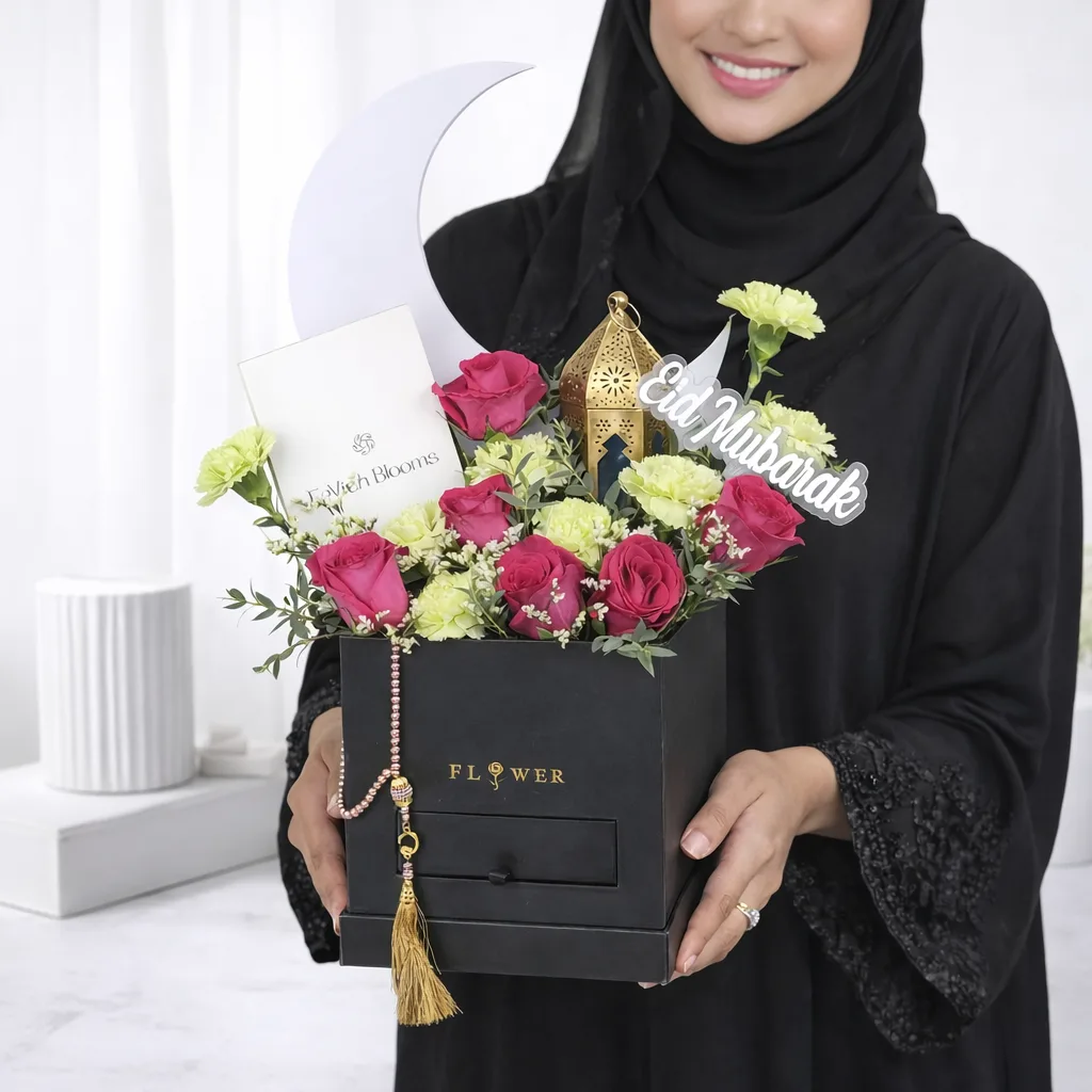 Woman in hijab holding an Eid Mubarak flower gift box with pink roses and gold lantern.