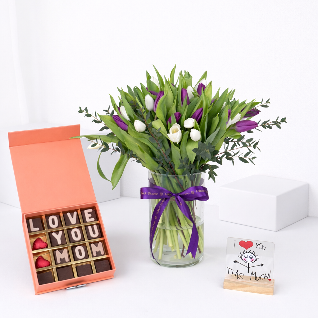 Purple and white tulip arrangement in glass vase with "Love You Mom" chocolate gift box and "I Love You This Much" greeting card.
