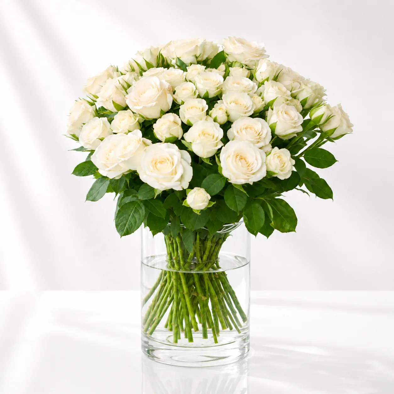Snow Blossom Elegance 21 white spray roses arranged in a clear glass vase