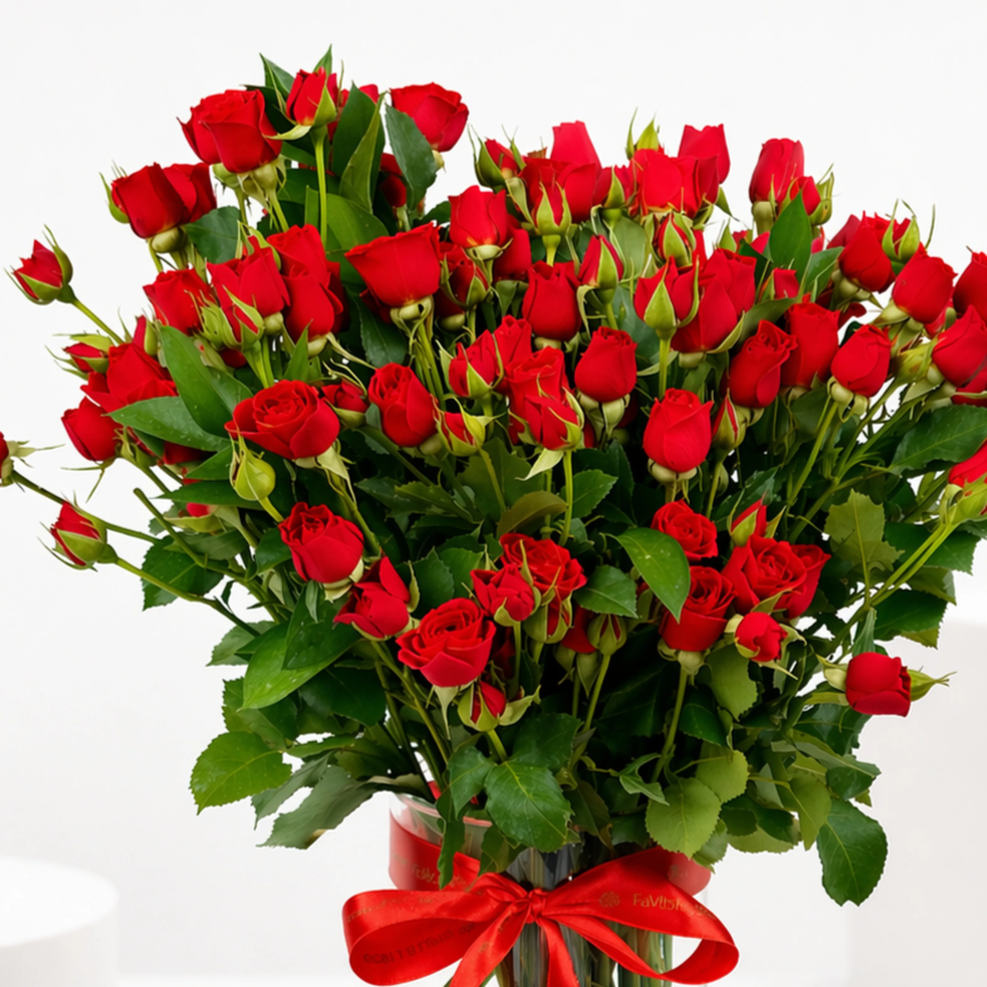 Close-up of vibrant red spray roses and buds in a glass vase tied with a red satin ribbon.