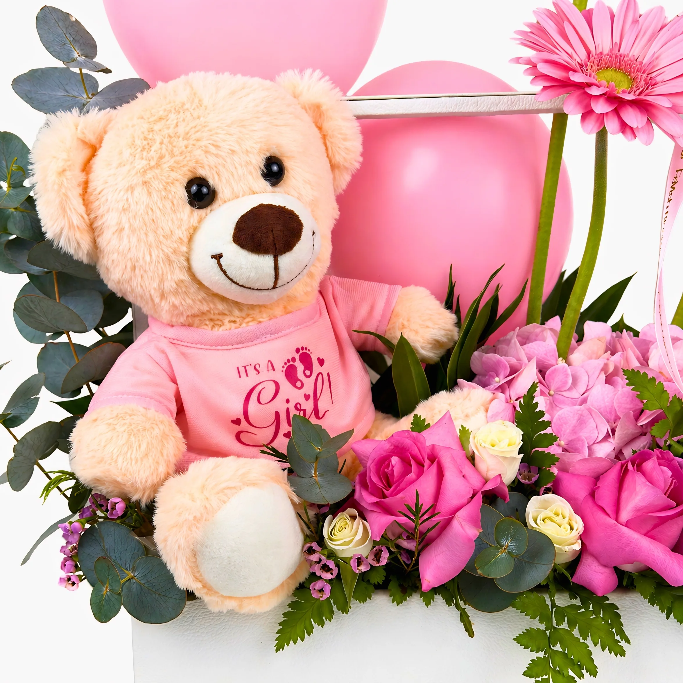 Close-up of baby girl teddy bear gift arrangement with pink balloons, pink roses, hydrangea, eucalyptus, and fresh greenery.