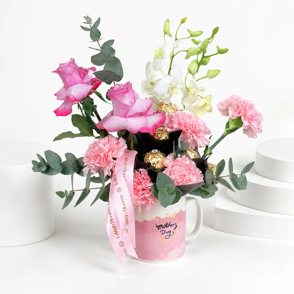 Pink floral mug arrangement with orchids, roses, carnations, and chocolates.