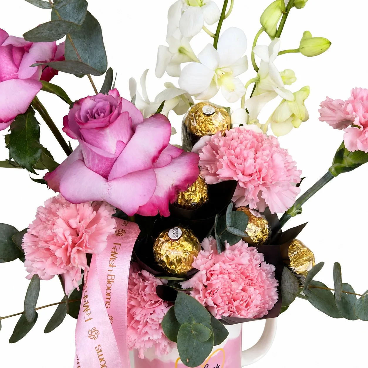 Close-up of pink floral mug with orchids, roses, carnations, and chocolates.