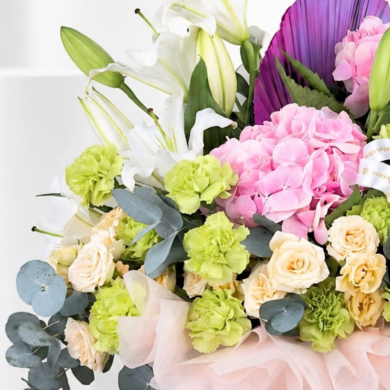 Pink hydrangeas, peach spray roses and green carnations in floral gift box