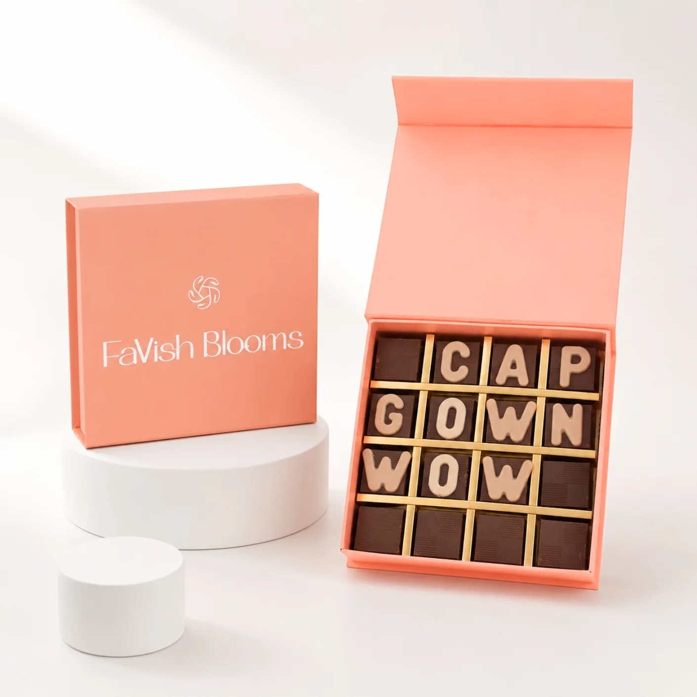 Premium “Cap Gown Wow” graduation chocolate gift box by FaVish Blooms with custom letter chocolates in elegant peach-orange packaging.