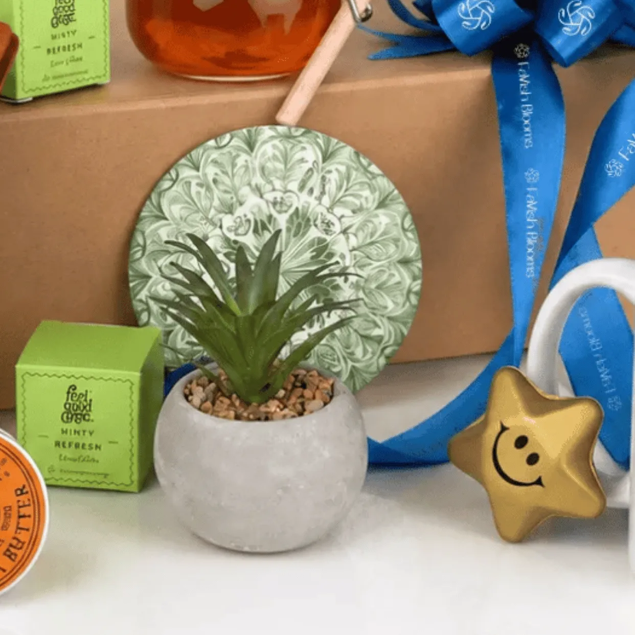 Close-up of Father’s Day premium gift hamper with mini plant, honey jar, blue ribbon gift box, Dad mug and skincare items