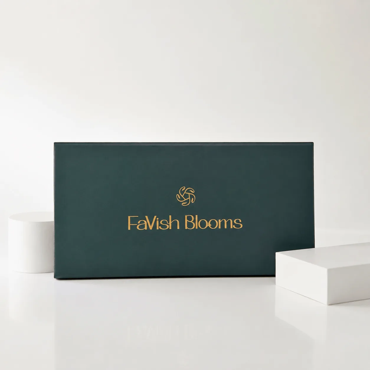 "Closed dark green FaVish Blooms gift box with gold logo and lettering."