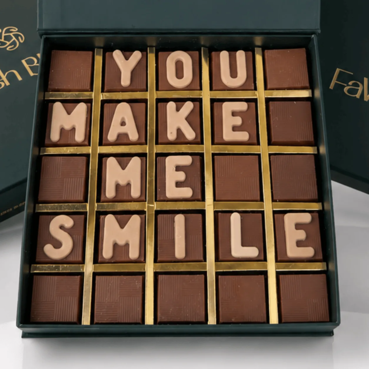 "Close-up of chocolate letter box spelling 'You Make Me Smile' in a green FaVish Blooms gift box."