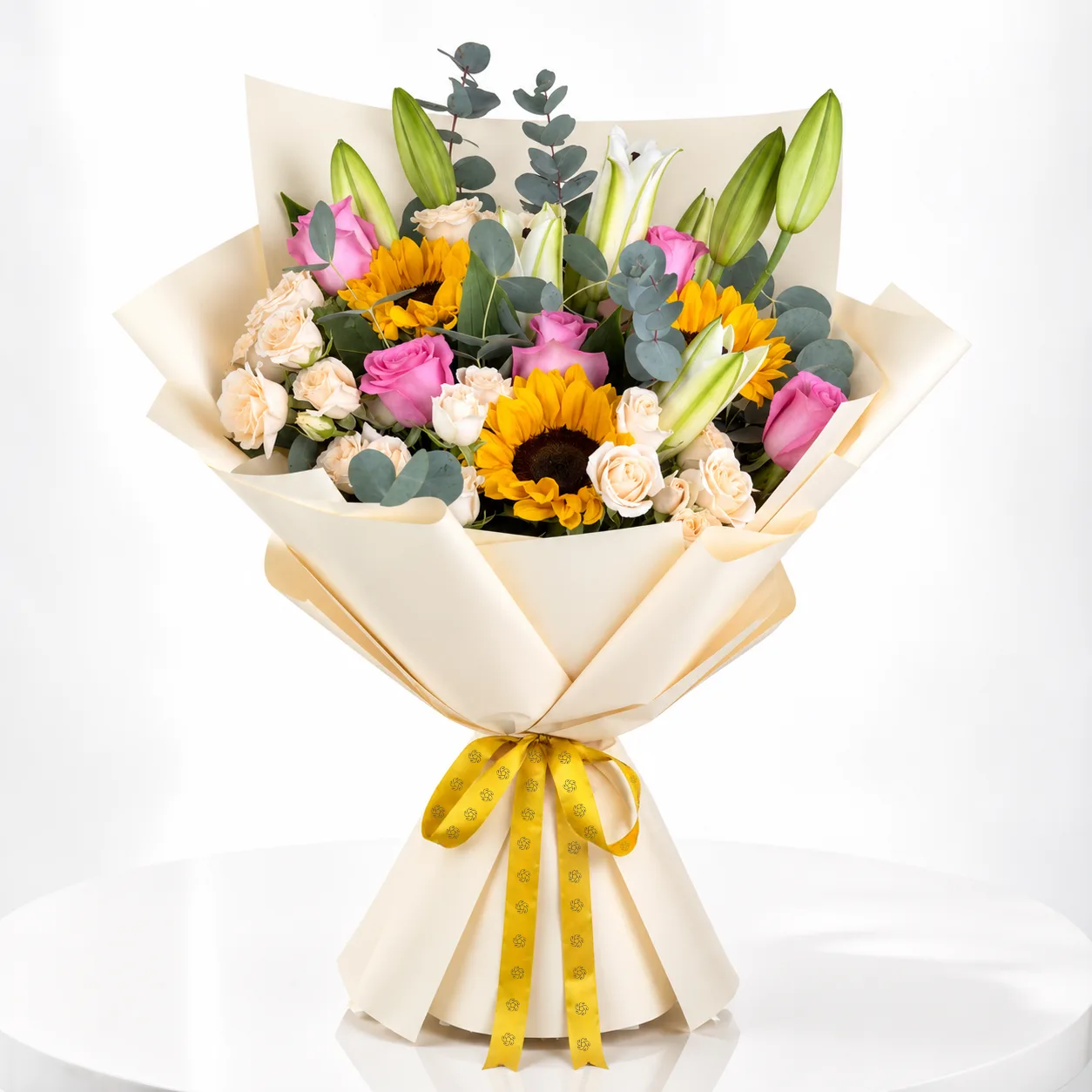 Mixed flower bouquet with sunflowers, pink roses, white lilies wrapped in cream paper