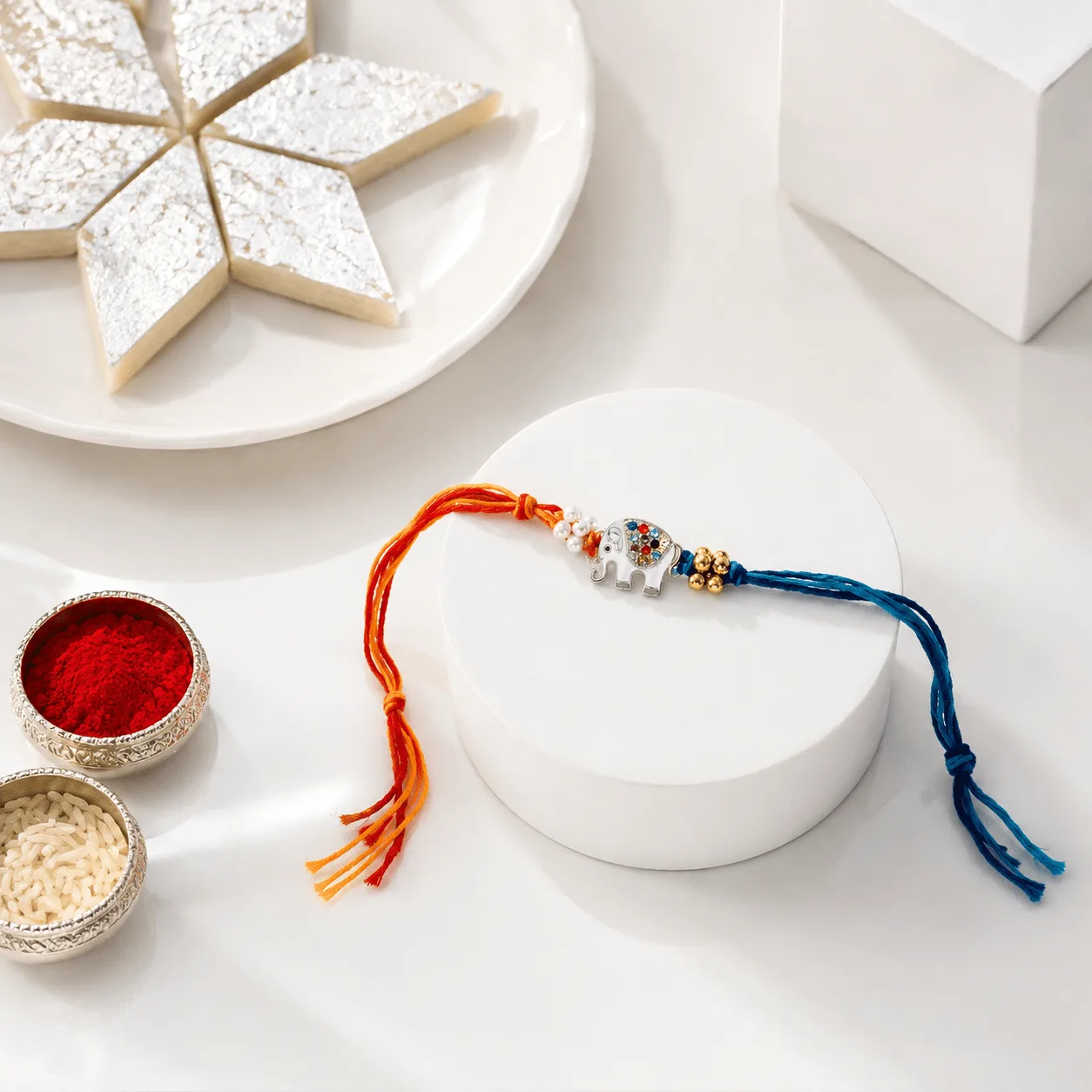 Raksha Bandhan gift box featuring assorted sweets, Ganesha idol, and children’s rakhis