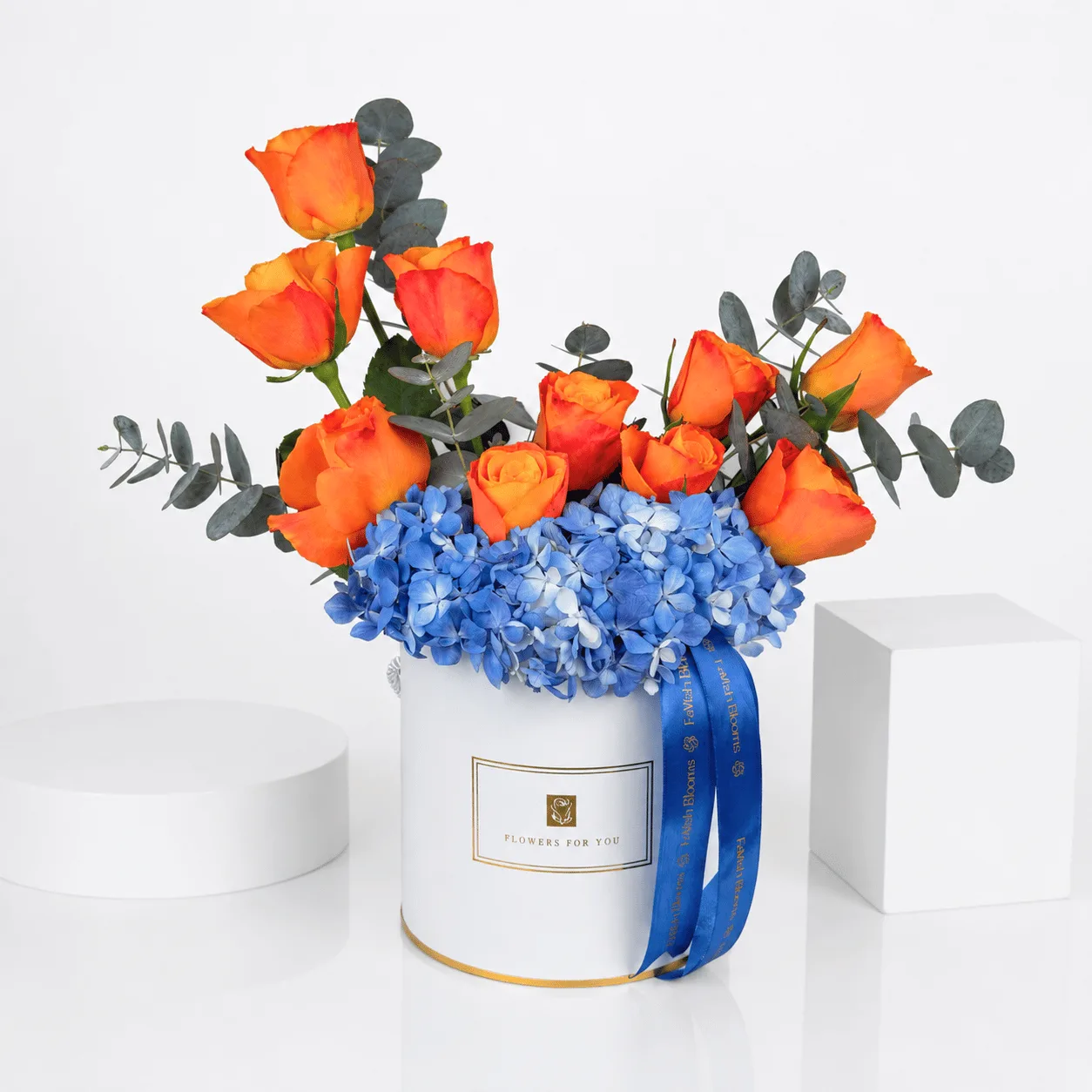 Orange roses and blue hydrangea in white FaVish Blooms box