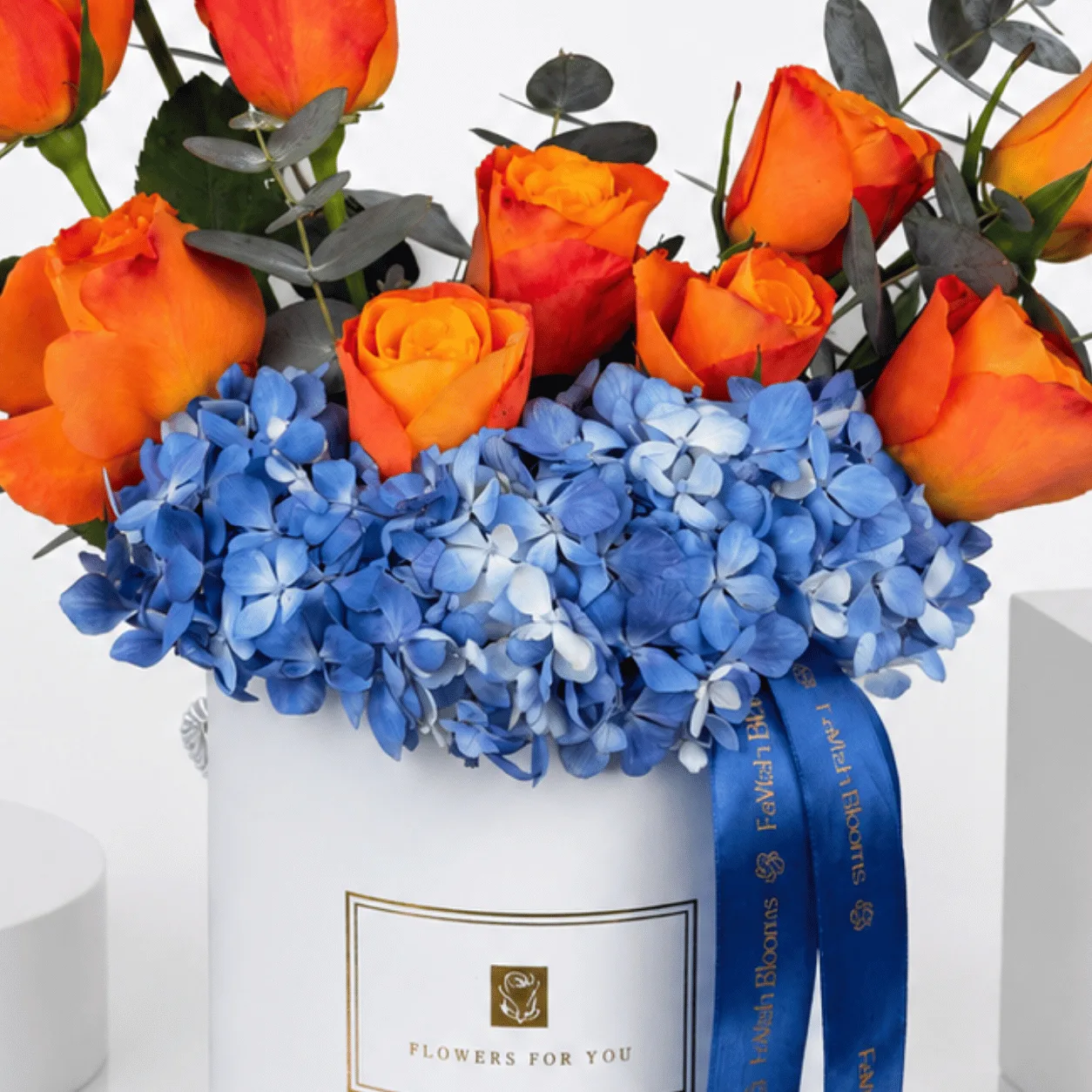 Orange roses and blue hydrangea in "Flowers For You" white box