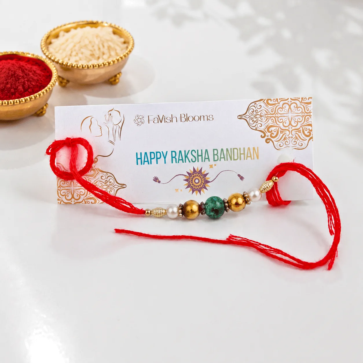 Green Beaded Rakhi with gold accents and pearl details on a traditional red thread for Raksha Bandhan celebrations